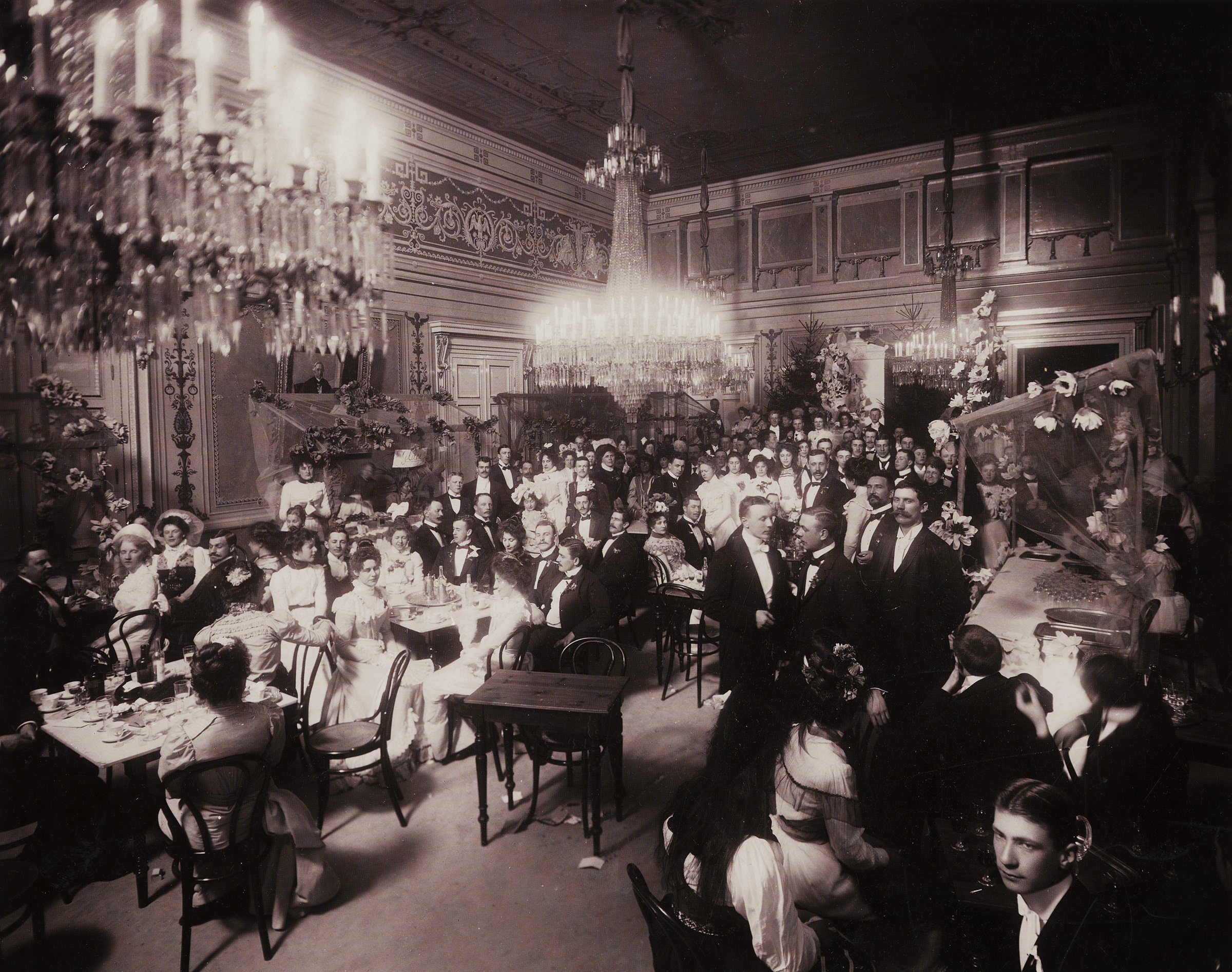 Uppklädda människor har samlats inne i Börsens festsal år 1895.